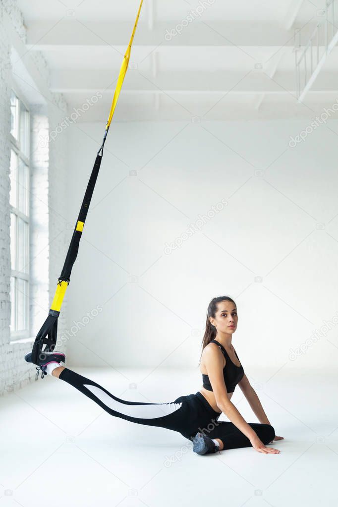 young woman doing yoga stretching exercises with trx fitness straps