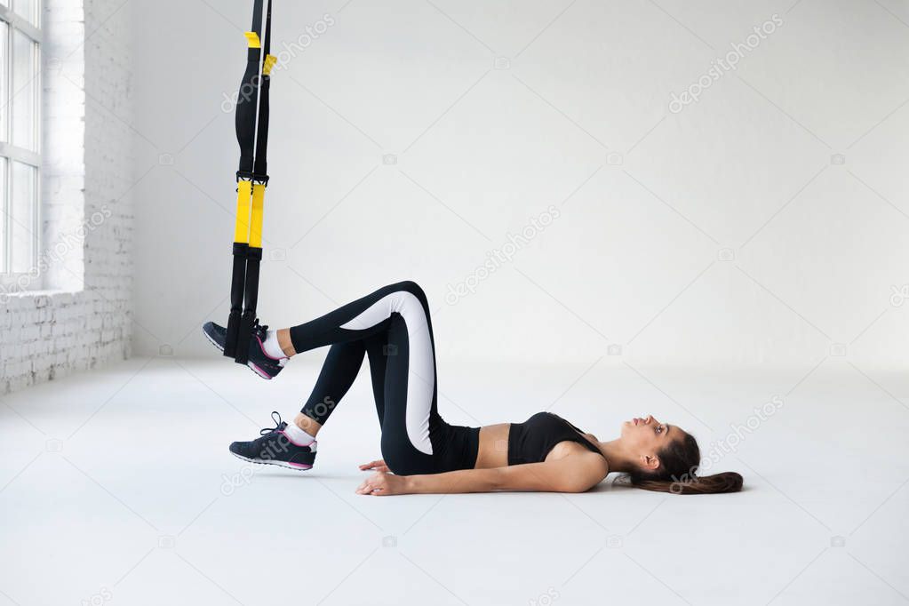 young woman doing yoga stretching exercises with trx fitness straps