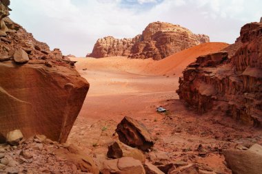 Wadi Rum çölde Safari jeep araba, Ürdün, Orta Doğu, Ay Vadisi. Turuncu kum, pus, bulutlar. Unesco Dünya Mirası Listesi'ne atılmıştır. Kızıl gezegen Mars manzarası. Offroad maceraları seyahat arka plan.