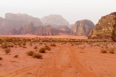 Wadi Rum çölü, Ürdün, Orta Doğu, Ay Vadisi. Kırmızı kum, dağlar ve pus. Unesco Dünya Mirası Listesi'ne atılmıştır. Milli park açık hava manzarası. Offroad maceraları seyahat arka plan. 
