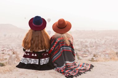 Otantik boho şık tarzı poncho giyen seyahat kadınlar, tatlı ve şapka Kapadokya vadisinde gökyüzünde hava ballons bakıyor. Seyahat ve wanderlust kavramı. Alan arka planını kopyalama.