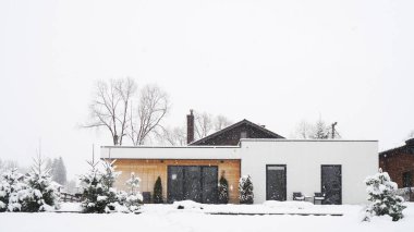 Güzel bir ev, karla kaplı yapraklarla çevrili sakin bir kış sahnesinde oturuyor. Samimi dış görünüşü, Noel kutlamaları için mükemmel bir mutluluk ve refah atmosferini davet ediyor..