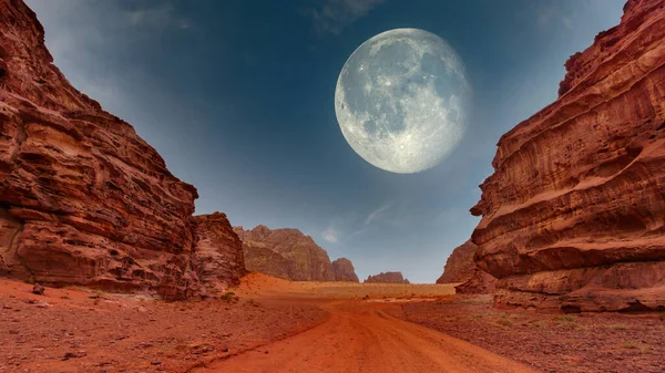 Her iki taraftaki görkemli kaya oluşumlarıyla çerçevelenmiş uçsuz bucaksız bir çöl uzanıyor. Parlak bir dolunay sahneyi aydınlatıyor, kumlu arazide yumuşak bir ışık yayıyor..