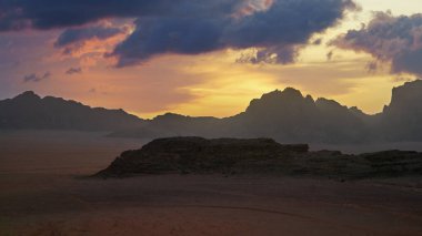 Çarpıcı bir günbatımı çöldeki engebeli dağları aydınlatıyor, gökyüzünde canlı renkler sergiliyor. Manzara, gezegenimizi korumak için sürdürülebilir uygulamalara duyulan ihtiyacı yansıtıyor..
