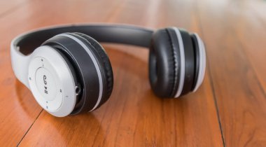 Beyaz kablosuz kulaklıklar ahşap bir masaya yerleştirilmiş.