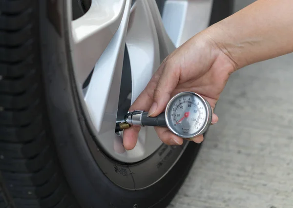 Measuring car tire pressure with air gauge. closeup