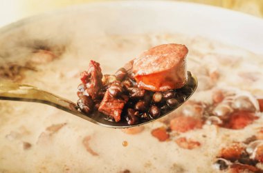 Kaşık Feijoada, Brezilya mutfağı pan maddeler dışarı alarak. Siyah fasulye, domuz eti ve sosis kaşıkla. Buhar zemin üzerine tavada pişirme feijoada.