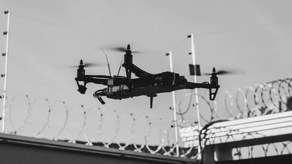 Black homemade drone invading a private property. Drone infringing the privacy of a restrict area recording with camera on a private property with barbed fence and electric fence.