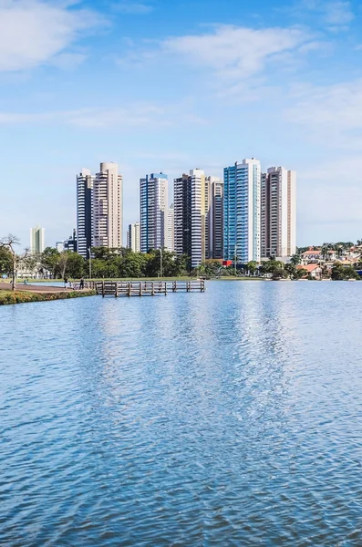 Lake of a urban park with a deck on a beautiful sunny day. The water of the lake with some buildings on the background and some nature around. Photo at Campo Grande MS, Brazil.