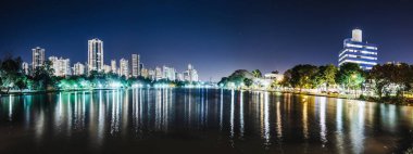 Panoramic photo of the Lago Igapo, Londrina - Parana, Brazil. View of the Igapo lake at night and the city, buildings on background. Leisure place, touristic destination of the city. clipart