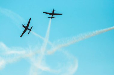 İki uçak hatları üzerinde gökyüzü birbirimizin yolu geçiş ve duman bir iz bırakarak arkasında. Uçaklar hava akrobasi sunum yapma. A-29 Super Tucano uçak. Metin için yer.