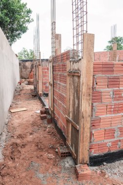 İnşaat, arazi bir duvar ev inşaatı altında. Betonarme yapısı. Ev tuğla, çelik rebars ve beton yapılmış. Bir evin yapısal parçaları. 