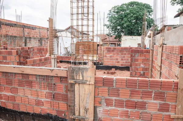Construction, land under construction of a masonry house. Structure of reinforced concrete. House made of bricks, steel rebars and concrete. Structural parts of a house.