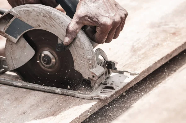 Hand of a carpenter using a circular saw to cut a wooden plank. Tool used to saw wood. Carpentry tool. Electric saw, circular blade.