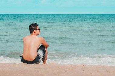 Plaj kumsalında oturan adam