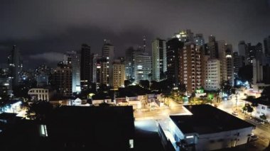 Geceleri Sao Paulo'nun timelapse videosu. Bulutlu bir gecede Sao Paulo şehrinin binaları. Bulutlar hızlı hareket ediyor. Aclimacao yerleşim mahalle, şehrin merkezi alan.