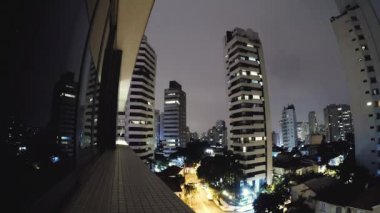 Geceleri Sao Paulo'nun timelapse videosu. Bulutlu bir gecede Sao Paulo şehrinin binaları. Bulutlar hızlı hareket ediyor. Aclimacao yerleşim mahalle, şehrin merkezi alan.