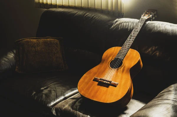 Guitarra acústica velha apoiada no sofá em casa — Fotografia de Stock