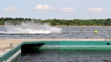 Scooter, yüksek hızda su kayma, ön planda gördüğümüz bir iskele.