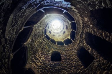SINTRA, PORTUGAL - FEBRUARY 5 2019: The famous initiation well of the Quinta da Regaleira, masonic spiral staircase of the romantic age in Sintra, Portugal, on february 5, 2019 clipart