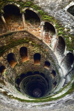 SINTRA, PORTUGAL - FEBRUARY 5 2019: The famous initiation well of the Quinta da Regaleira, masonic spiral staircase of the romantic age in Sintra, Portugal, on february 5, 2019 clipart