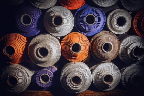 Muitos rolos têxteis de cores azul, branco e laranja empilhados um — Fotografia de Stock