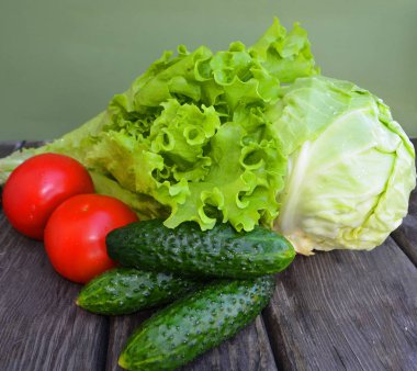 Sepette taze salatalık. Arka planda lahana, maydanoz, kırmızı turp, marul, domates. Geleneksel tarz. Vejetaryen gıdalar.