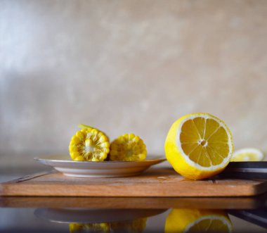 Tahta bıçak ile kesme üzerinde sarı Mısır kesip limon