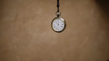 sallanan bir sarkaç gibi bir kablosunun üzerine askıya vintage cep saati
