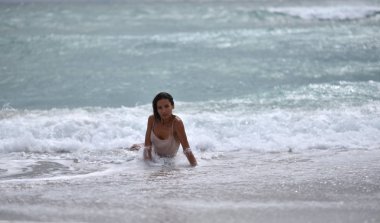 deniz tarafından kumlu bir plajda ıslak elbiseli kız