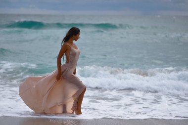 deniz tarafından kumlu bir plajda ıslak elbiseli kız