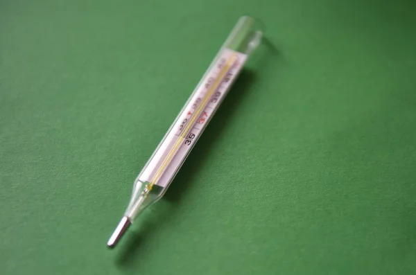 mercury thermometer and tablets on a green background