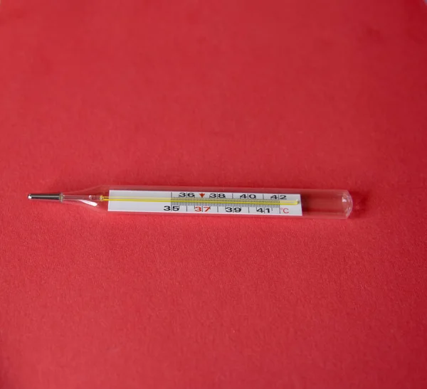 mercury thermometer on red background