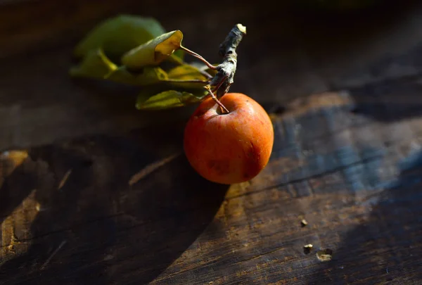 Olgun bir elma, gün ışığında tahta bir masanın üzerinde.