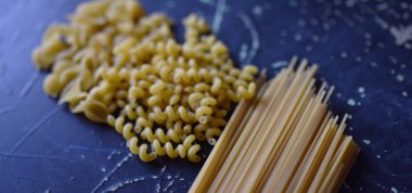 Koyu arkaplanda farklı şekillerde makarna