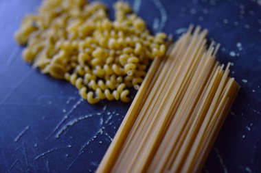 Koyu arkaplanda farklı şekillerde makarna