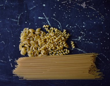 Koyu arkaplanda farklı şekillerde makarna