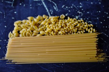 Koyu arkaplanda farklı şekillerde makarna