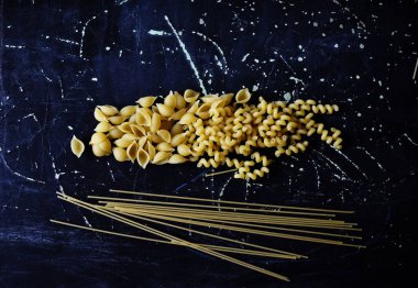 Koyu arkaplanda farklı şekillerde makarna