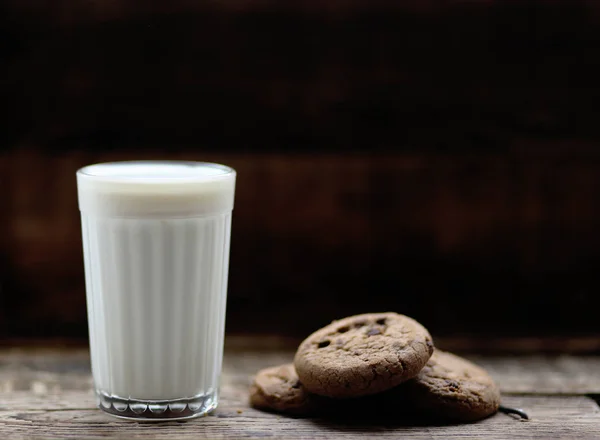 木の板の上にチョコチップをかけたミルククッキーのガラス — ストック写真