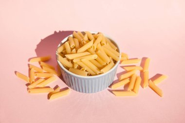 Pembe arka plan, geleneksel İtalyan yemekleri üzerine mavi kapta makarna penne