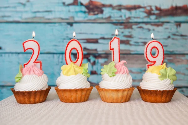 Mutlu yeni yıl 2019, vintage mavi ahşap arka plan üzerinde sayı mum ile cupcakes