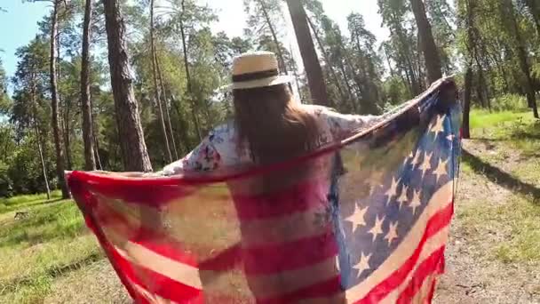 幸せなアメリカの女の子のダンスとジャンプの公園 アメリカの国家概念でアメリカ国旗を — ストック動画