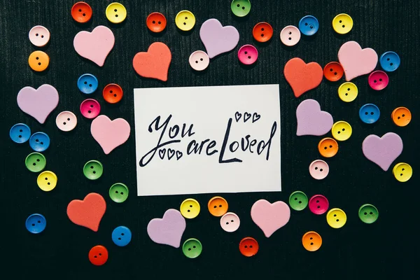 You are loved - text on black background with hearts decorations, religion and feelings concept