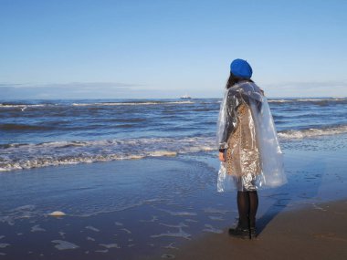 Kız bir yağmurluk deniz ayakta  