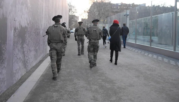 Militer dengan senjata di Paris. Di samping mereka adalah seorang wanita. Pemandangan dari belakang dalam pertumbuhan penuh. horisontal. Desember 2018 — Stok Foto