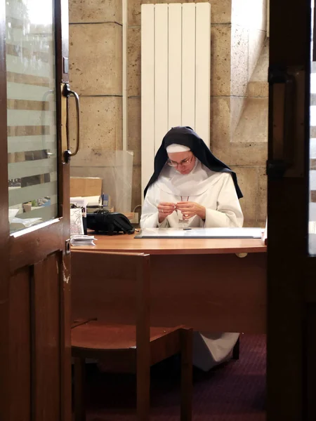 Paris, 6 Parvis Notre-Dame - Pl. Jean-Paul II, Notre Dame Cathedral, December 20, 2018. Монахиня сидит за столом и держит цепь с крестом — стоковое фото