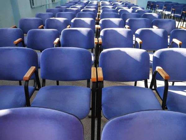 many blue chairs stand in a row. conference room without people during the day. horizontally