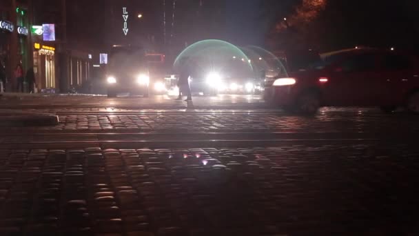 La gente borrosa cruzando la calle en la ciudad por la noche con coches, tráfico de luz y edificios como fondo, la vida nocturna en Ucrania Prores Codec — Vídeo de stock