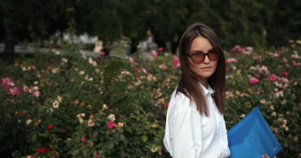 Schöne Geschäftsfrau mit blauem Ordner in der Hand und Sonnenbrille, die Codec-Zeitlupe bevorzugt — Stockvideo